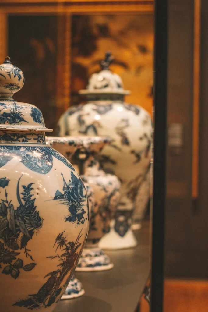 Collection d'urnes funéraires en porcelaine décorée exposées dans une vitrine.