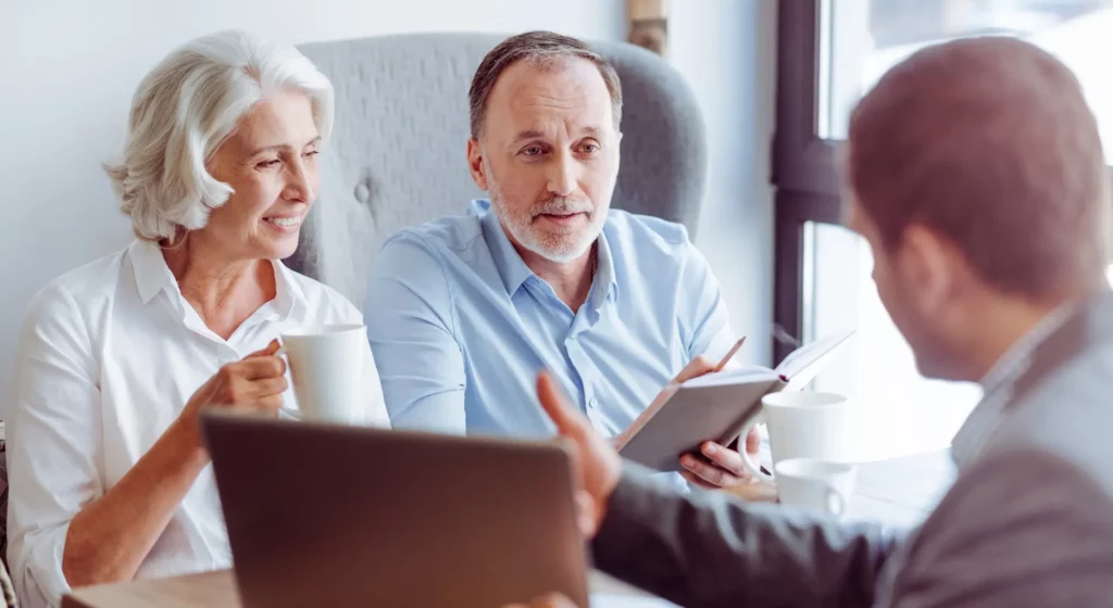 Un couple de seniors en rendez-vous de prévoyance obsèques avec un conseiller funéraire.